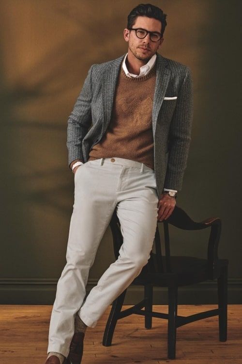 Man i smart casual med grå kavaj, stickad tröja och ljusa byxor